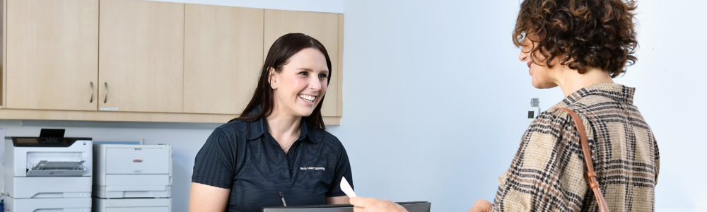 A female patient talks to a receptionist at a North Coast Radiology clinic